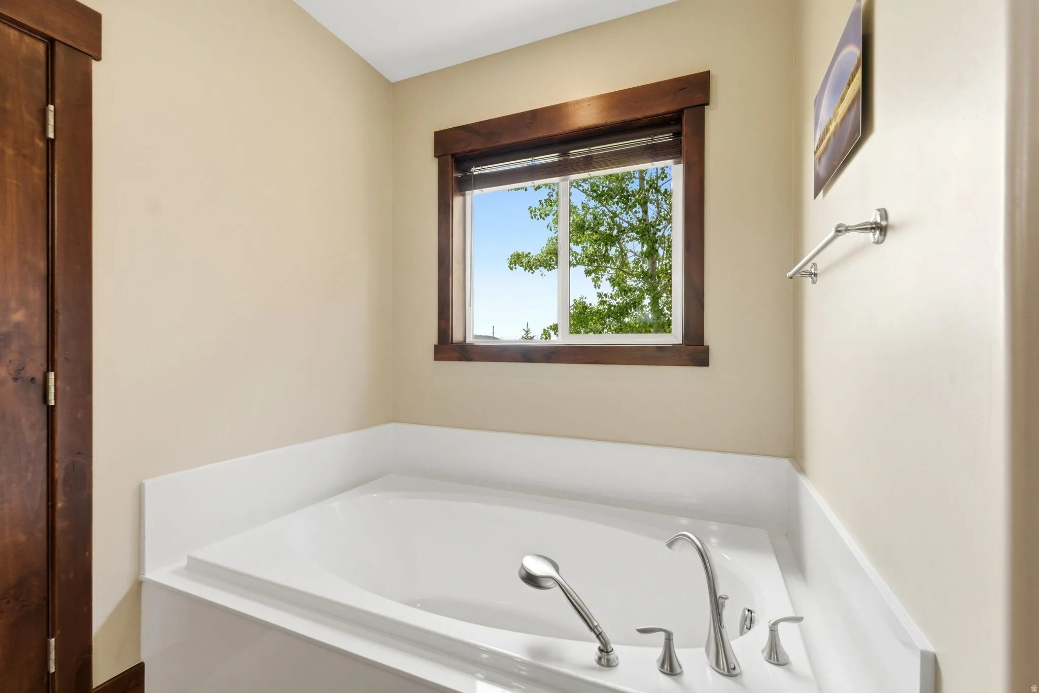 Built-in soaking tub with deck-mounted chrome fixtures, including a handheld shower sprayer