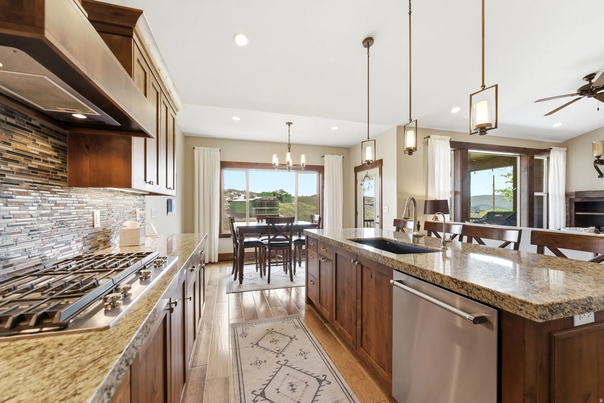 Gourmet kitchen with wood-finish flooring, granite countertops, and a full tile backsplash