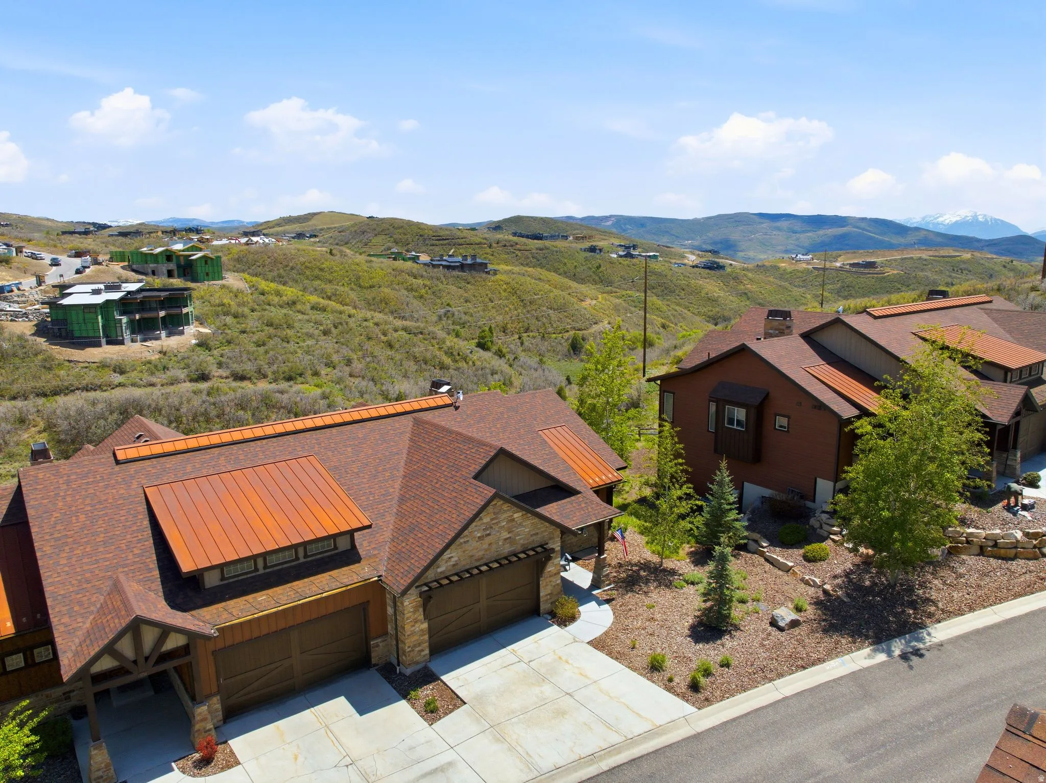 Contemporary mountain-style residence featuring a stone and wood siding facade, a multi-car garage, and a concrete driveway