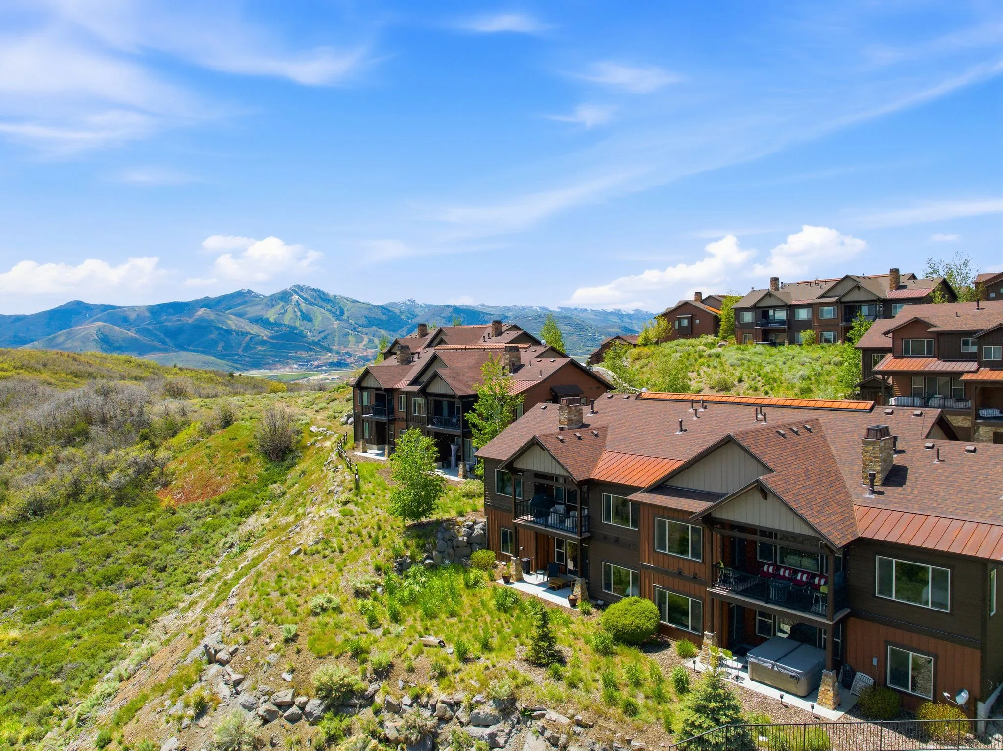 Multi-level property with dark wood siding, balconies, and a stone chimney