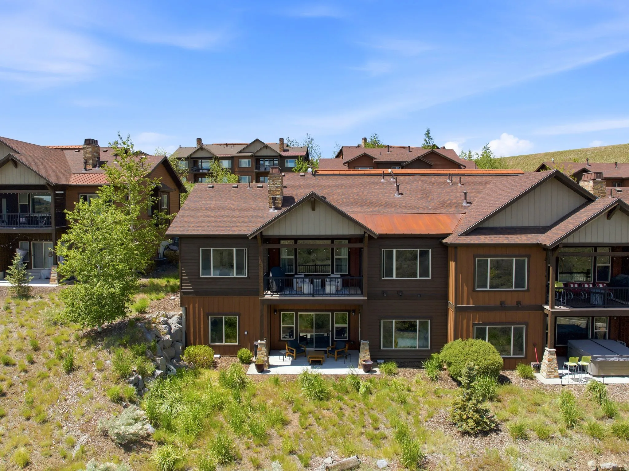 Multi-level property with a brown facade and sloped shingle roofing