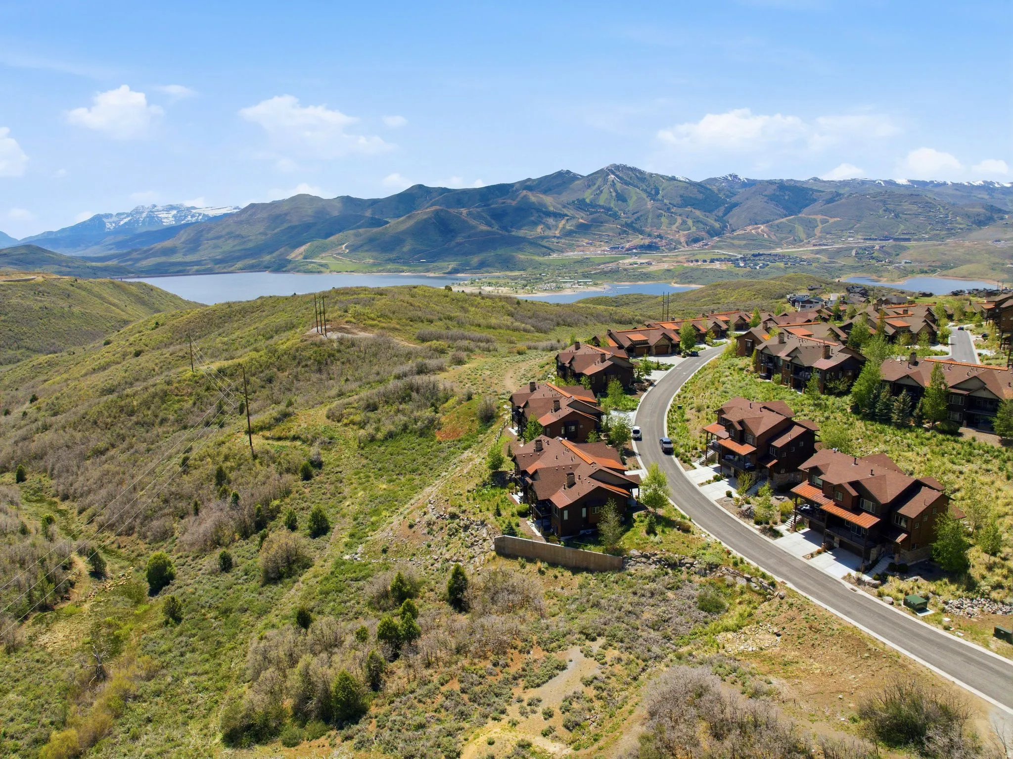 Mountainous terrain featuring a lake and a winding road with multiple residential structures