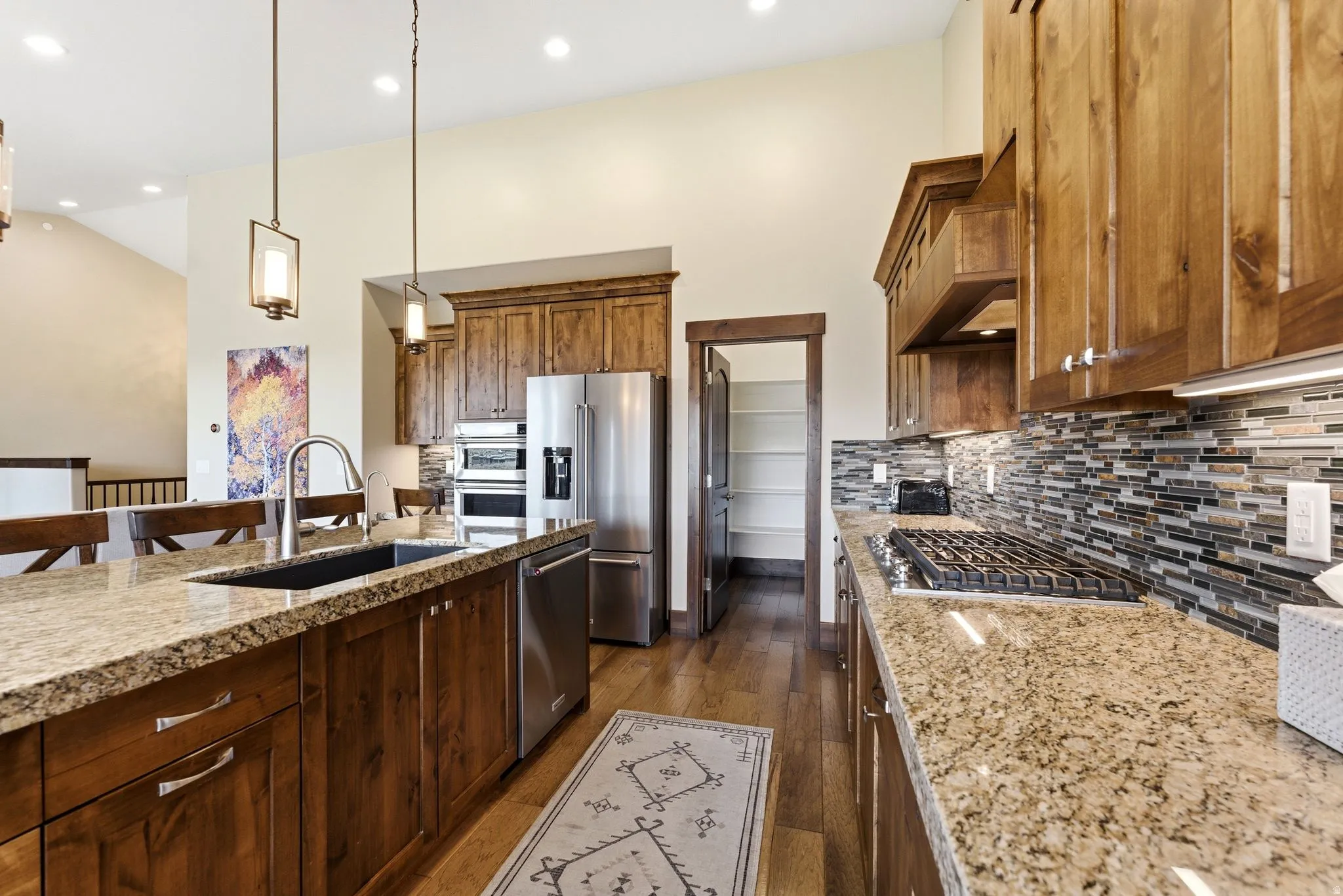 Kitchen featuring wood cabinetry, granite countertops, stainless steel appliances, a gas cooktop, and a mosaic tile backsplash