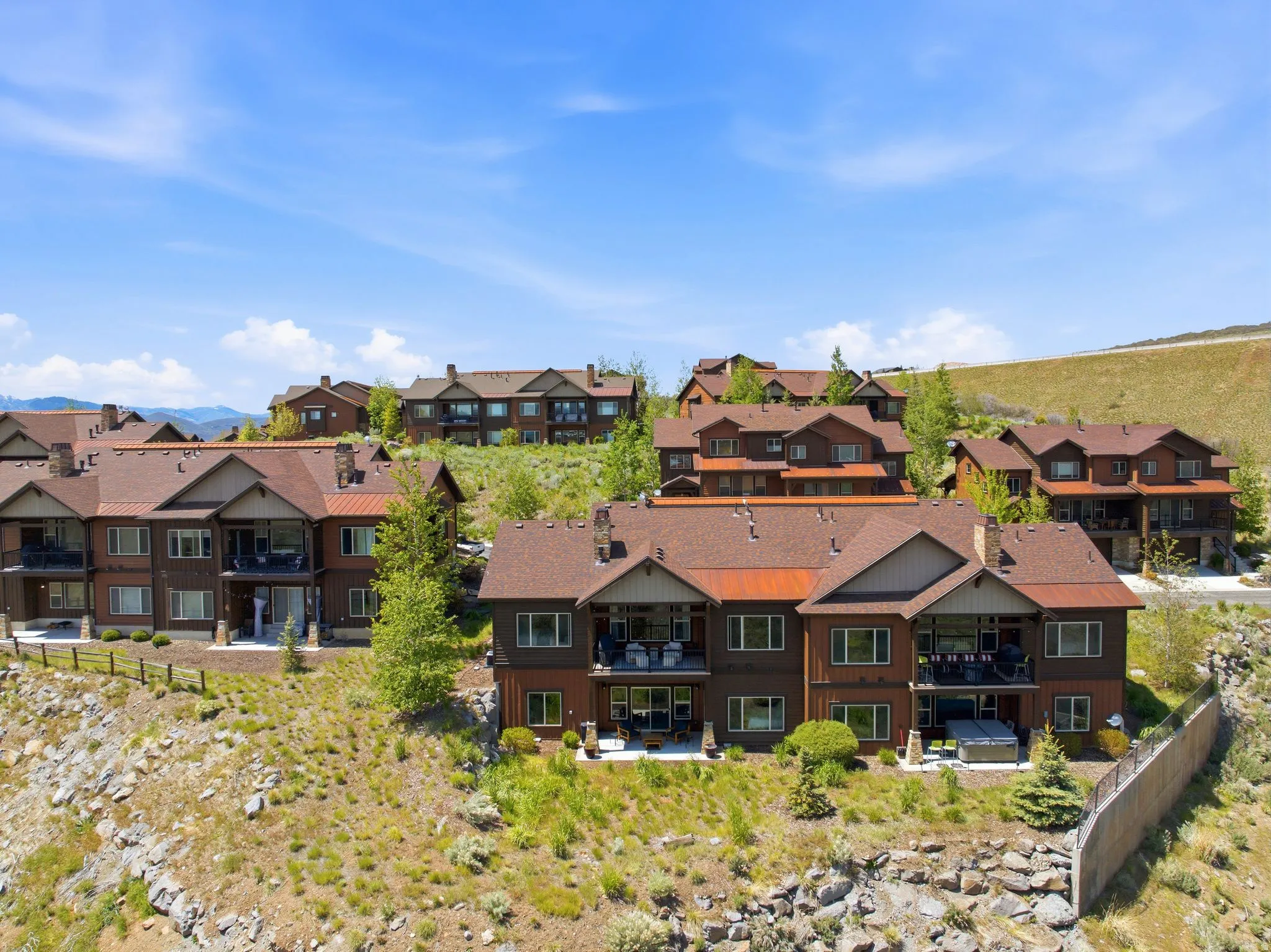 Hillside residential development featuring multi-level structures with brown siding and complementary brown shingle roofs