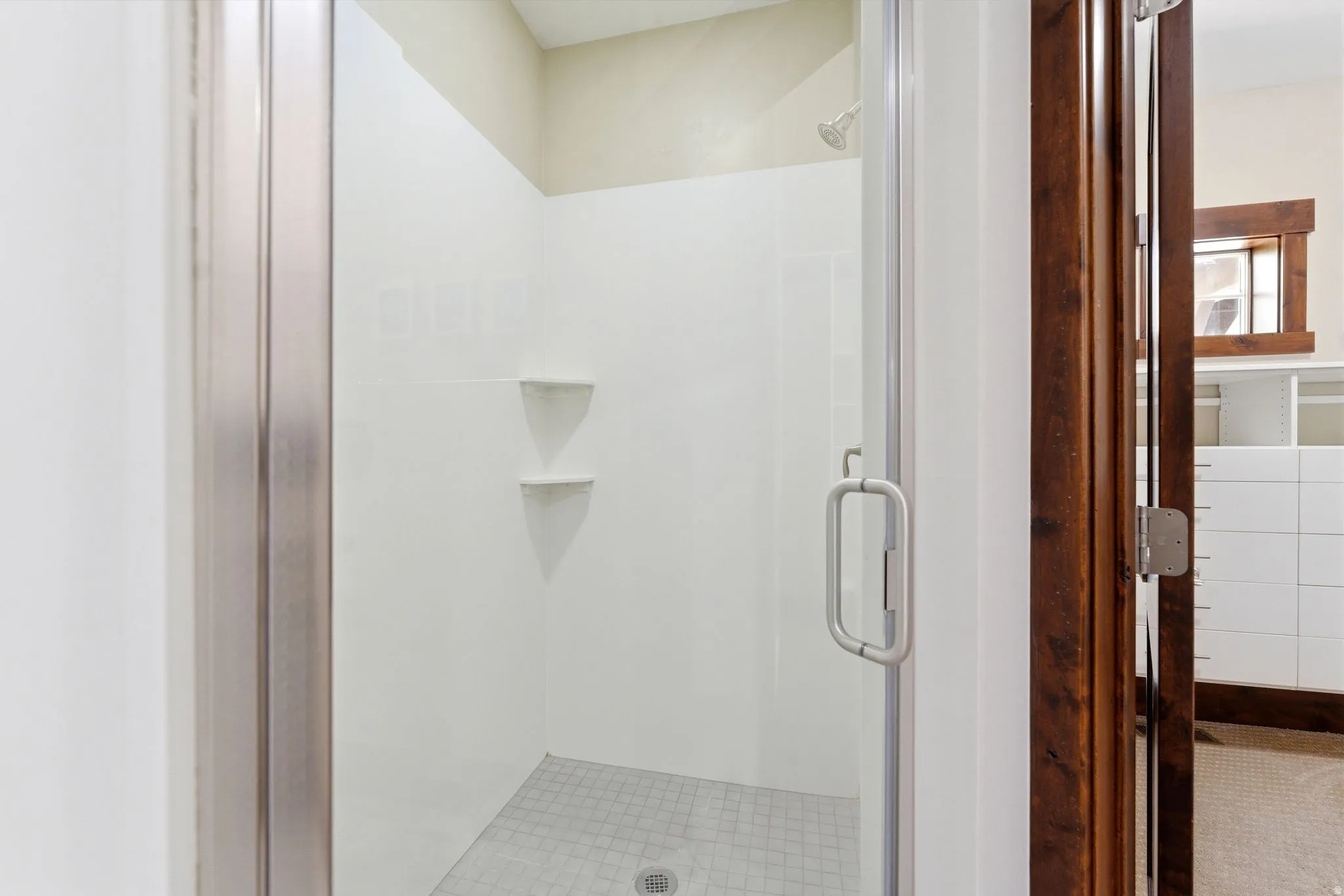 Tiled shower with glass enclosure, integrated shelving, and a rain showerhead