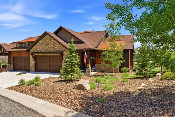 Stone and wood-sided exterior featuring a prominent two-car garage with carriage-style doors