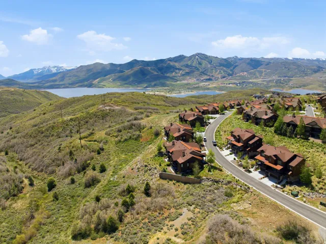 Mountainous terrain featuring a lake and a winding road with multiple residential structures