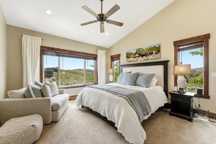 Bedroom featuring a vaulted ceiling with a ceiling fan, recessed lighting, and expansive windows with dark wood trim