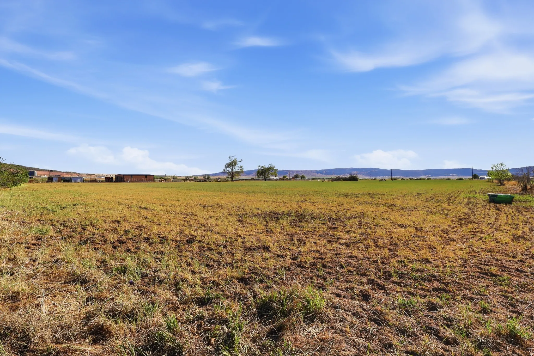 Expansive undeveloped land with a distant tree line and rolling hills