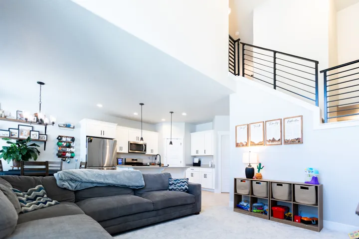 Open-concept living space with a kitchen featuring white cabinetry, stainless steel appliances, and a central island with countertop seating