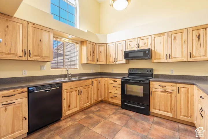 Functional kitchen featuring extensive wood cabinetry, dark countertops, and black appliances including a range, microwave, and dishwasher