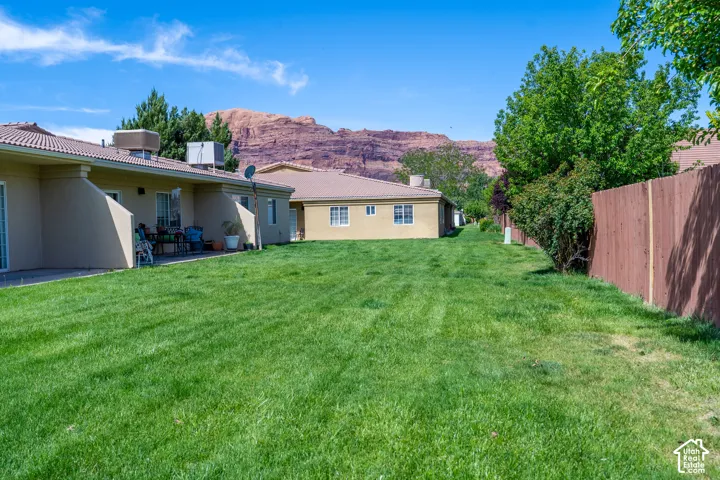 Expansive green lawn with mature trees and a privacy fence