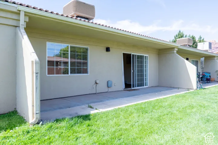 Expansive backyard featuring a concrete patio, sliding glass door access, and a large window with grid panes