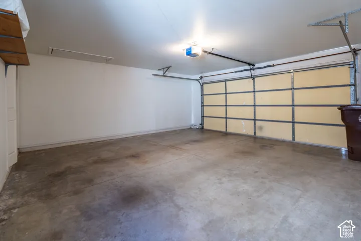 Spacious garage featuring a concrete floor, overhead lighting, and an automatic garage door opener