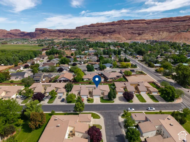Residential neighborhood featuring mature trees and prominent red rock formations in the background