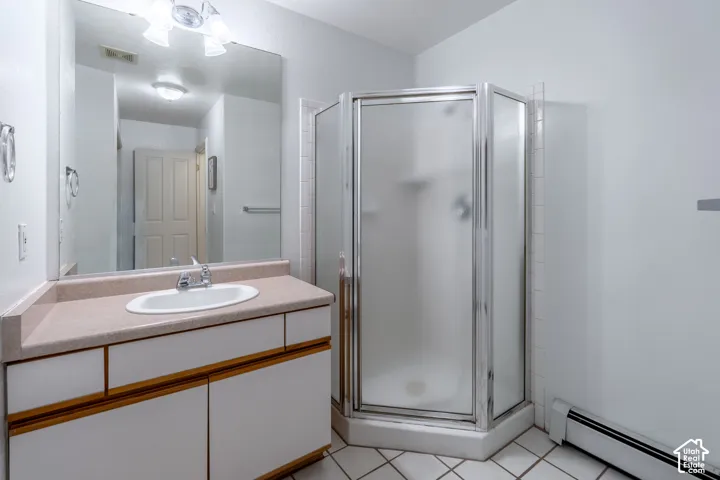 Bathroom featuring a corner shower with frosted glass enclosure, a single vanity with a laminate countertop, and a large wall-mounted mirror