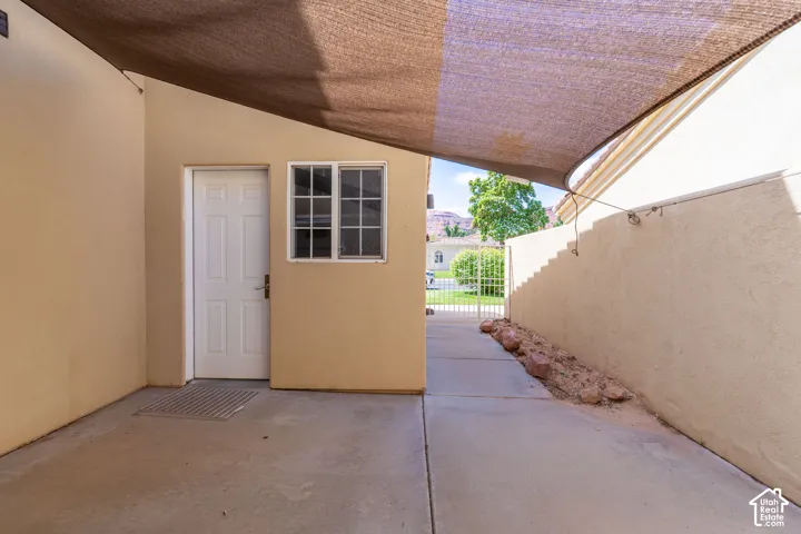 Covered patio with concrete flooring, accented by an exterior door and window with gridded panes