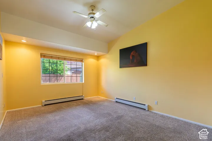 Carpeted interior space featuring a window with blinds, a ceiling fan, recessed lighting, and baseboard heating