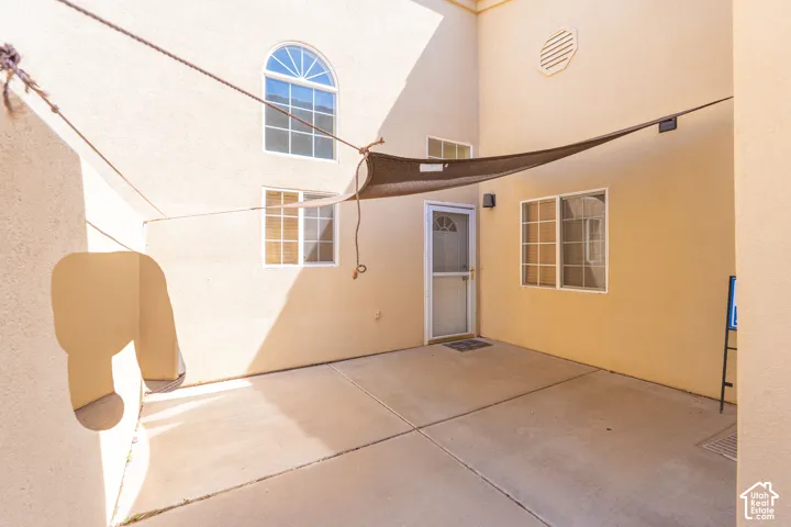 Private patio with concrete flooring, multiple windows, and exterior entry door with screen