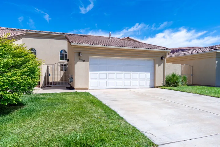 Front exterior with an attached garage, featuring a concrete driveway, stucco siding, and a tile roof
