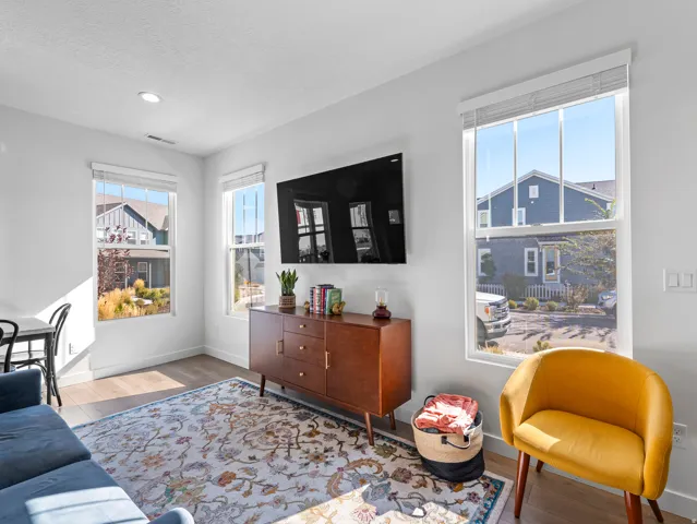 Bright living area featuring wood-finish flooring, recessed lighting, and multiple windows with white blinds