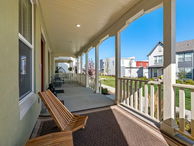 Expansive covered porch featuring a concrete floor, white balusters, recessed lighting, and a textured green exterior wall
