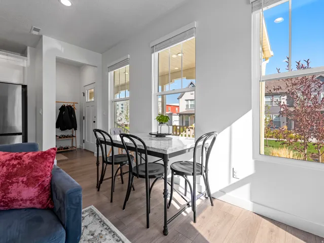 Dining area featuring a marble-finish table, tall windows with white trim, wood-finish flooring, and recessed ceiling lighting