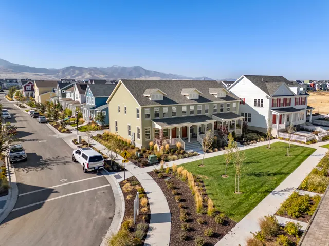 Contemporary multi-story residence with a light green exterior siding, multiple dormer windows, and a covered porch