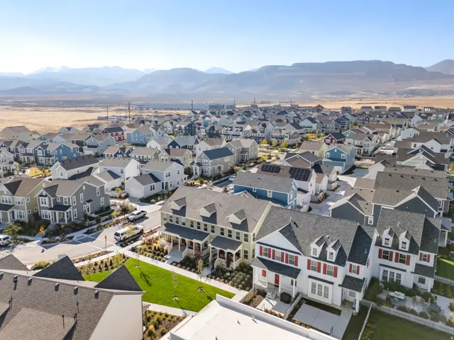 Expansive community with varied architectural styles, asphalt shingle roofs, and distinct landscaping, framed by distant mountains