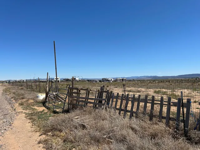 Expansive undeveloped land featuring a partial perimeter fence and distant mountain ranges