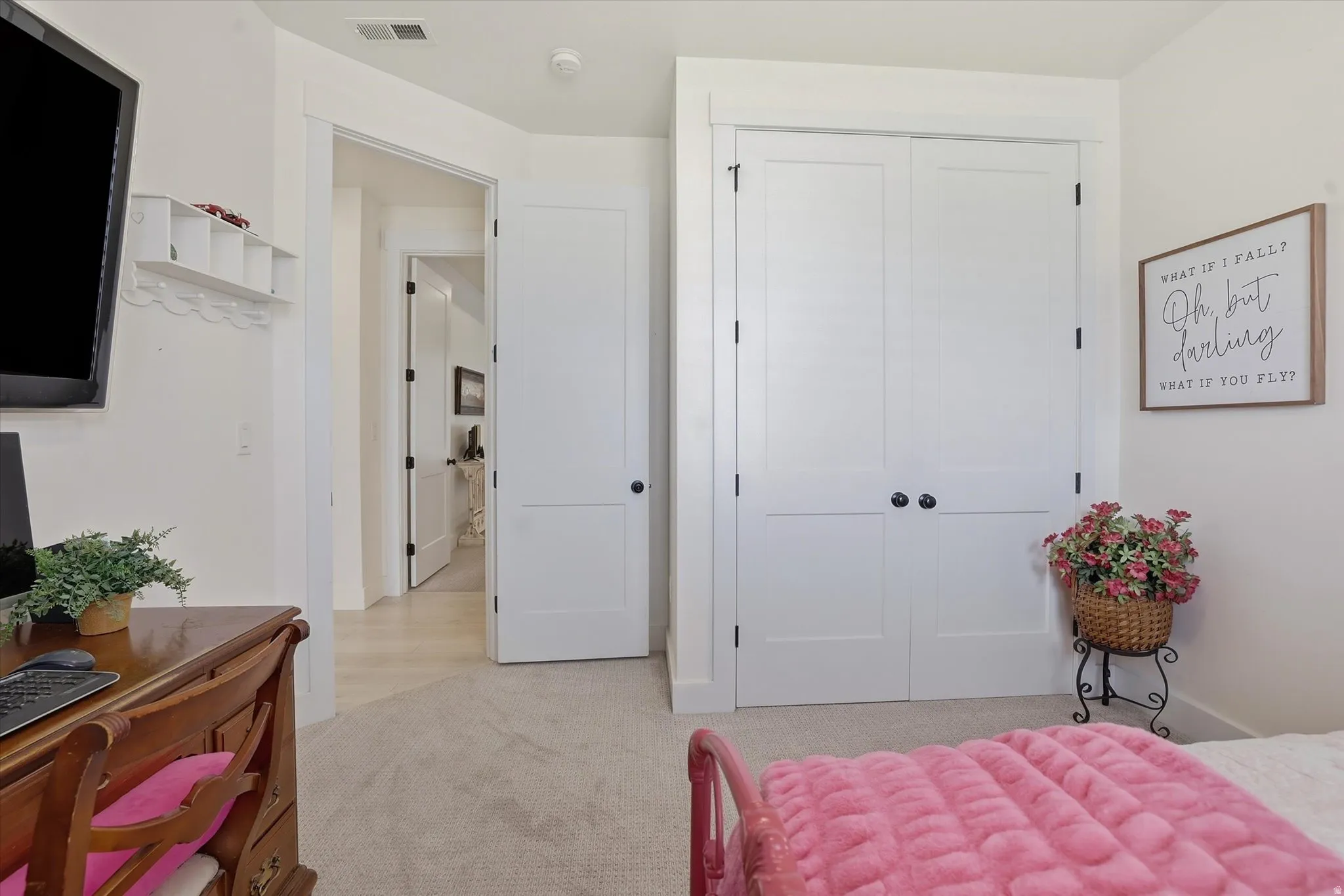 White painted bi-fold closet doors with black hardware, light neutral carpeting, and a white painted door frame