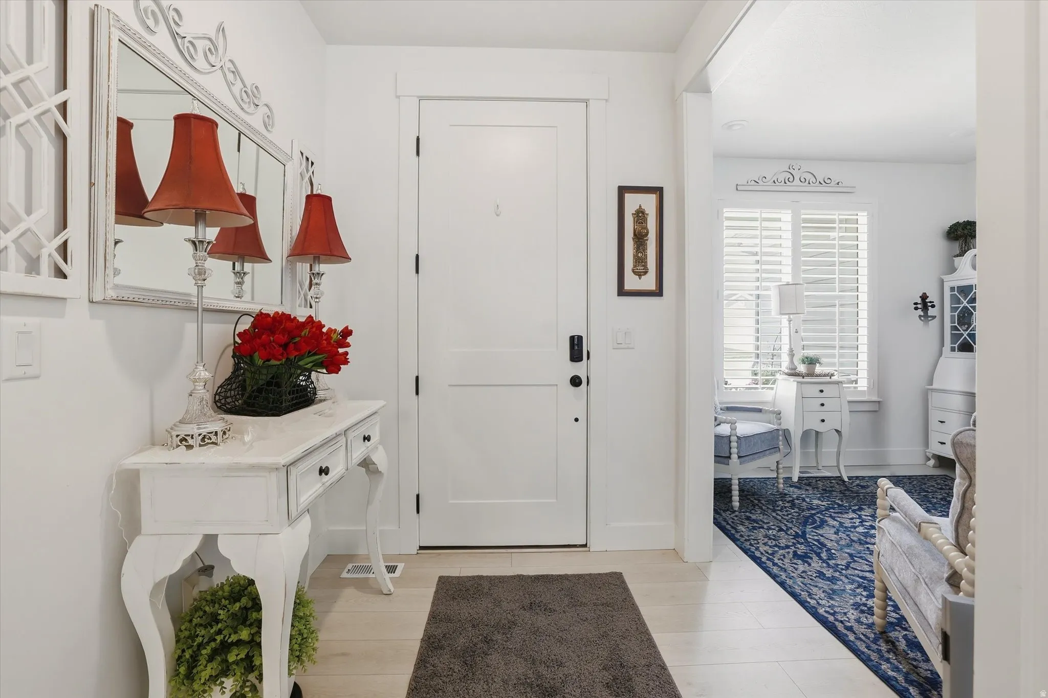 Entryway featuring a solid panel door with dark hardware, light wood-finish flooring, and a decorative console table