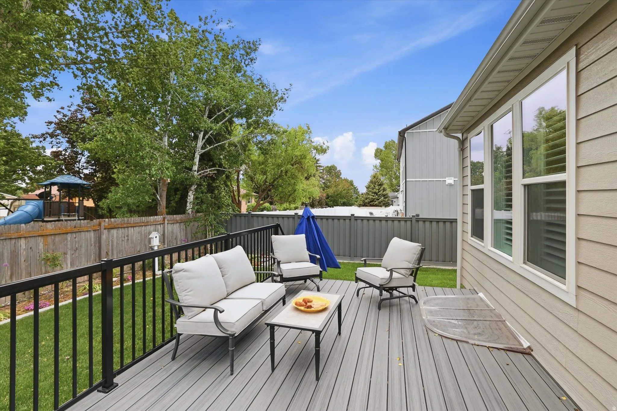 Spacious composite deck featuring a black metal railing and direct access to a level lawn