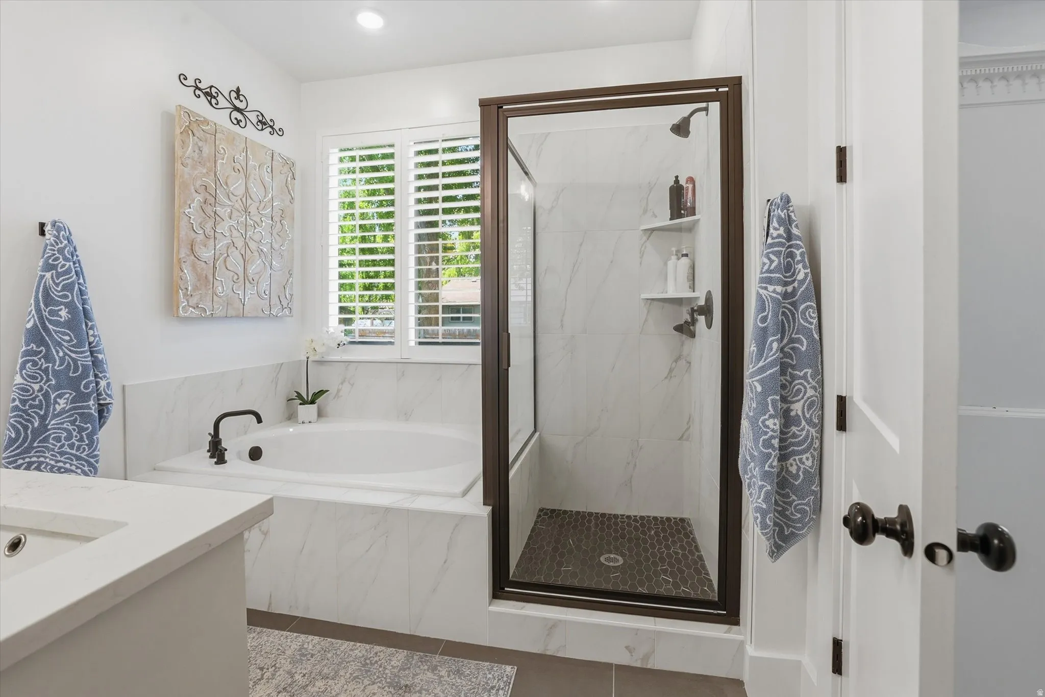 White marble-finish tile surrounds a built-in tub with a black faucet