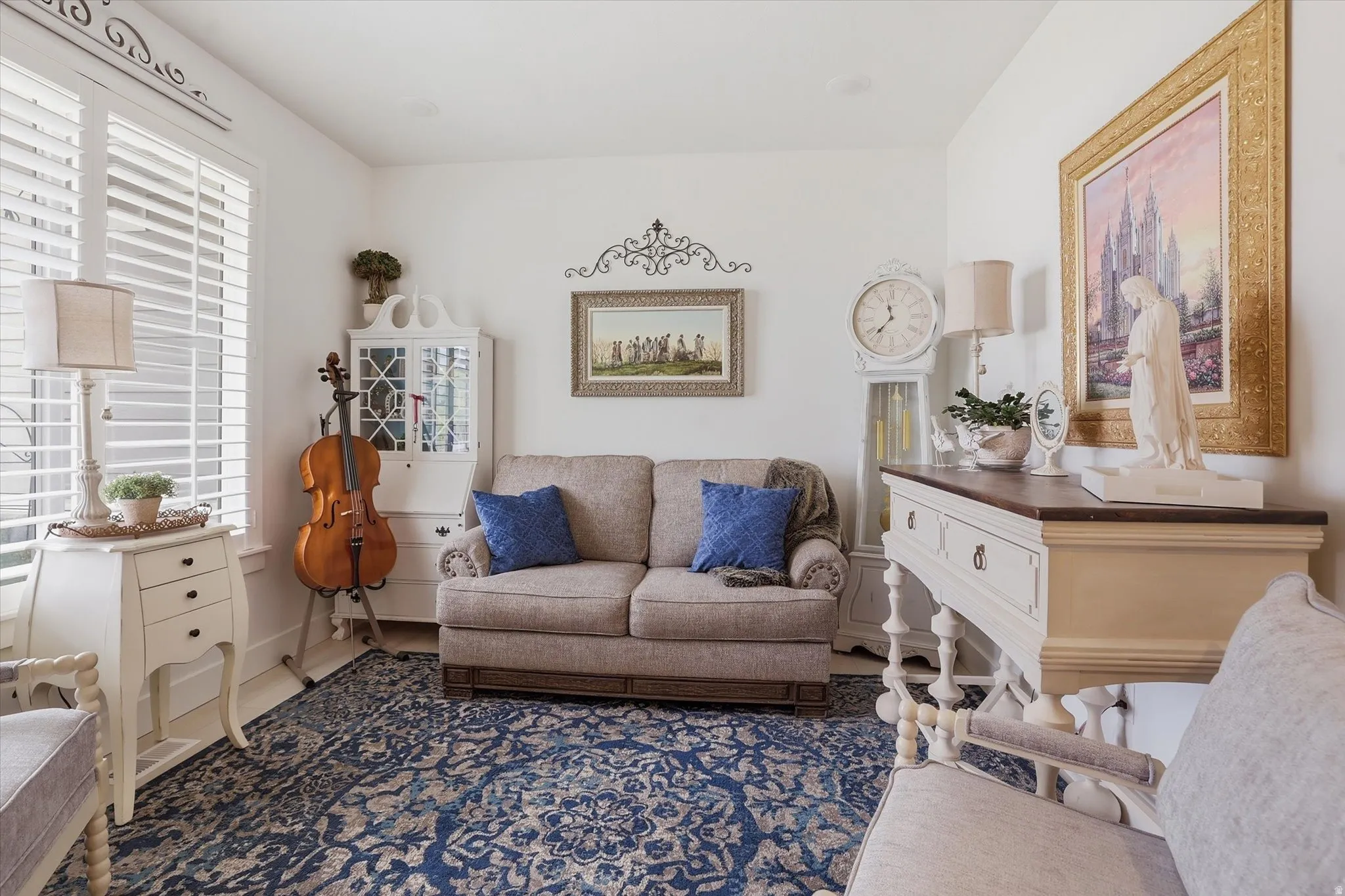 Living space featuring plantation shutters, white walls, and a patterned area rug