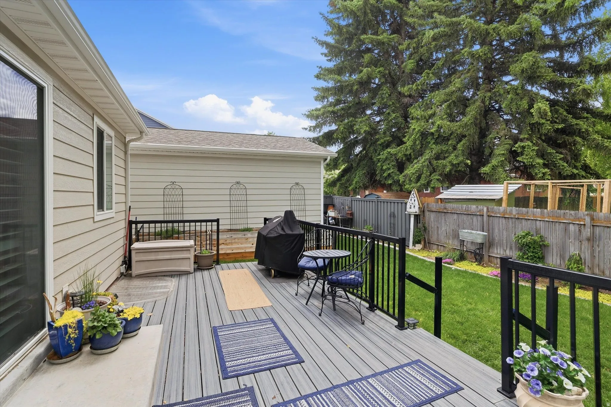 Composite decking with black metal railings, a manicured lawn, and a perimeter wood fence