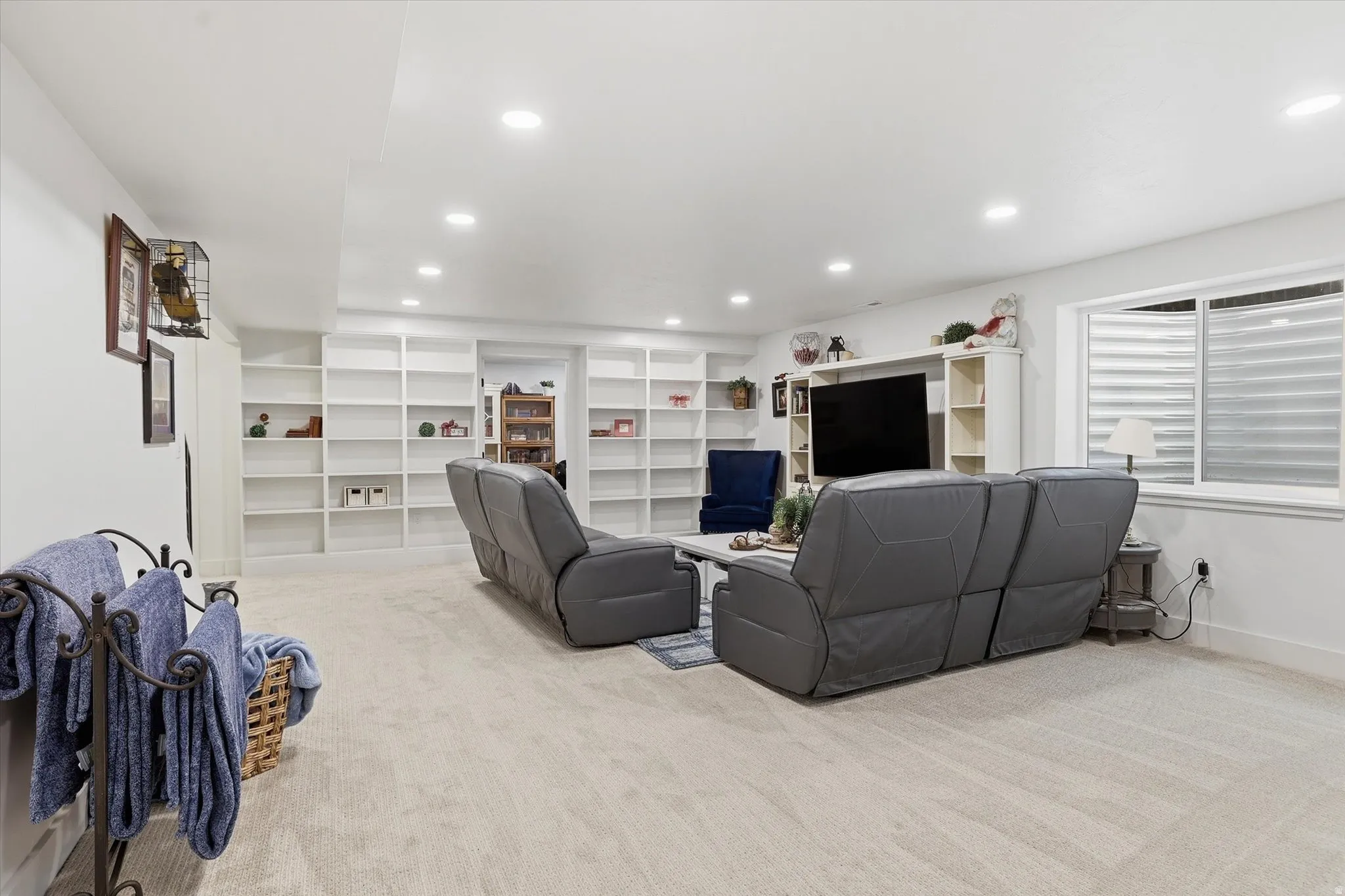 Spacious room featuring extensive built-in shelving, recessed lighting, and a neutral carpeted floor