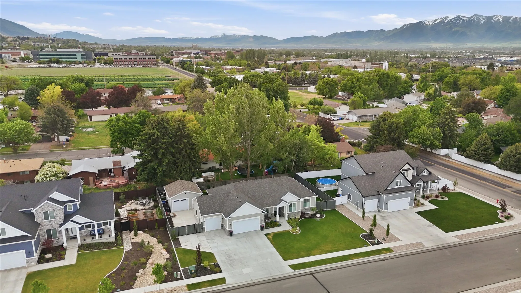 Modern residential streetscape featuring a single-story property with a two-car garage, mature landscaping, and a fenced backyard