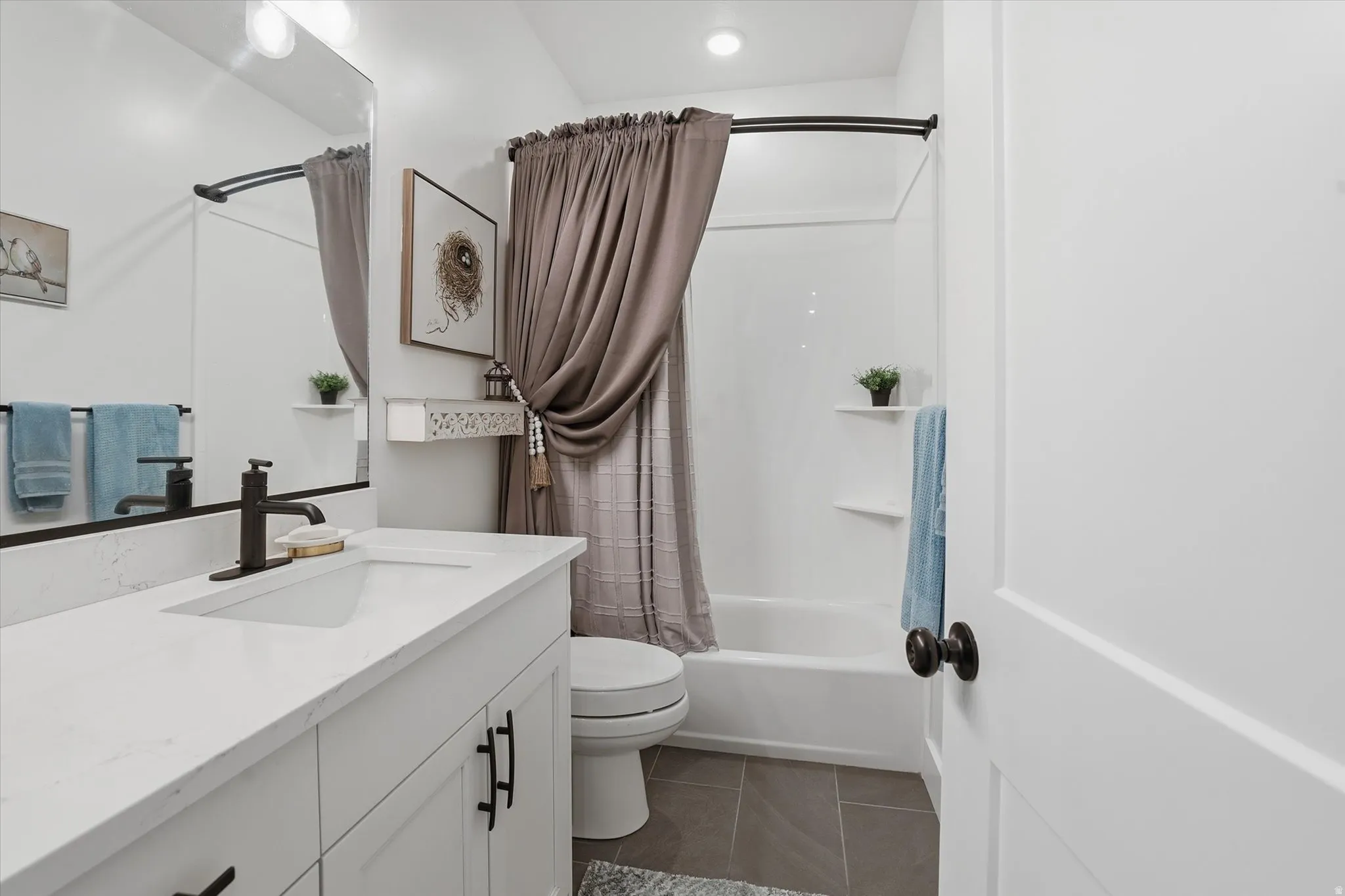 Bathroom featuring a white vanity with an integrated sink, dark bronze fixtures, and a spacious mirror