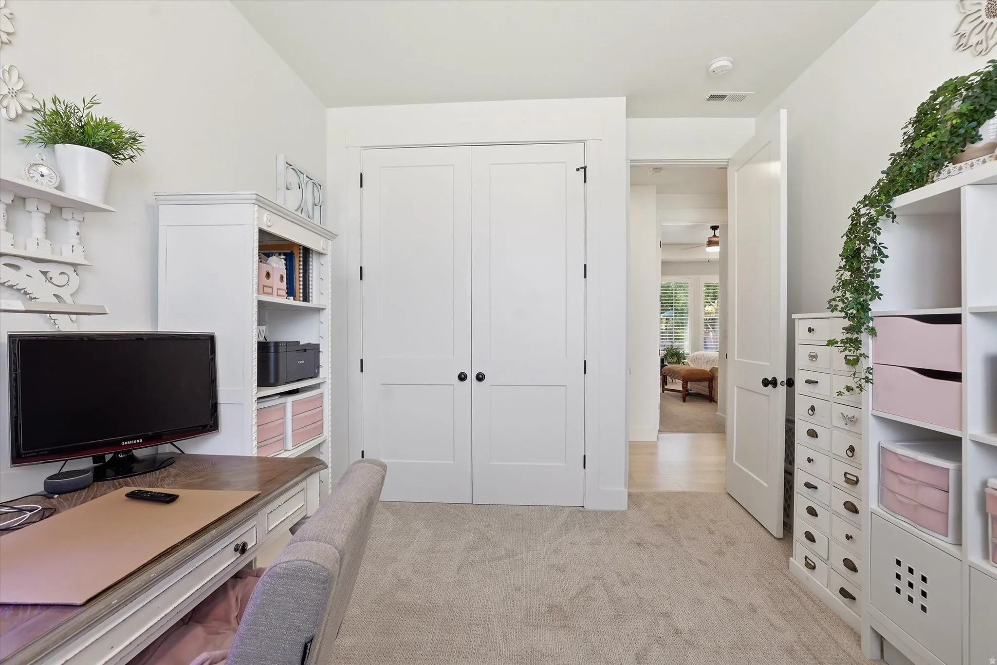 Carpeted room with double panel doors, white trim, and built-in shelving units
