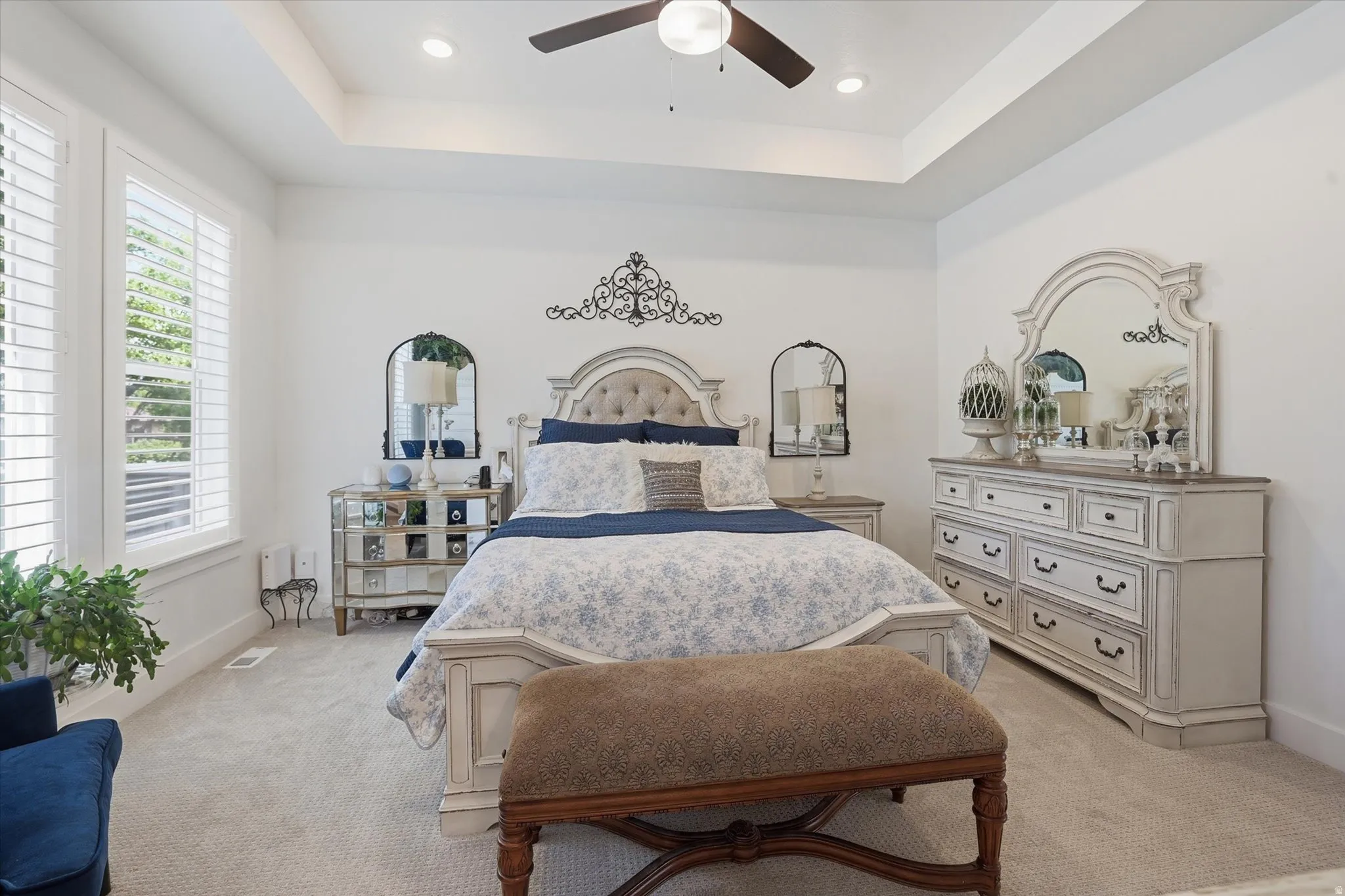 Recessed lighting illuminates a tray ceiling and a ceiling fan