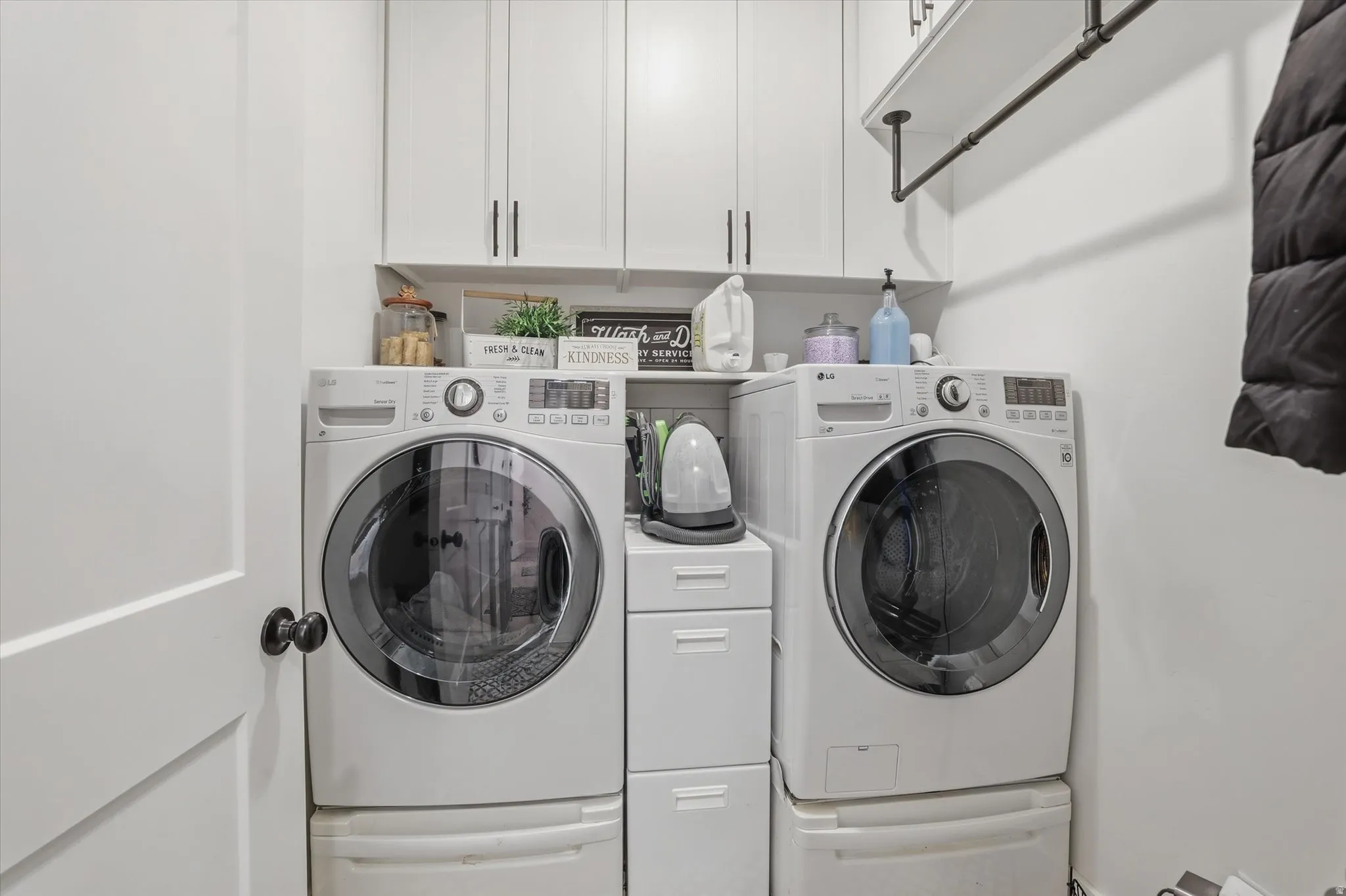 Laundry area featuring white cabinetry with black hardware, open shelving, and a hanging rod