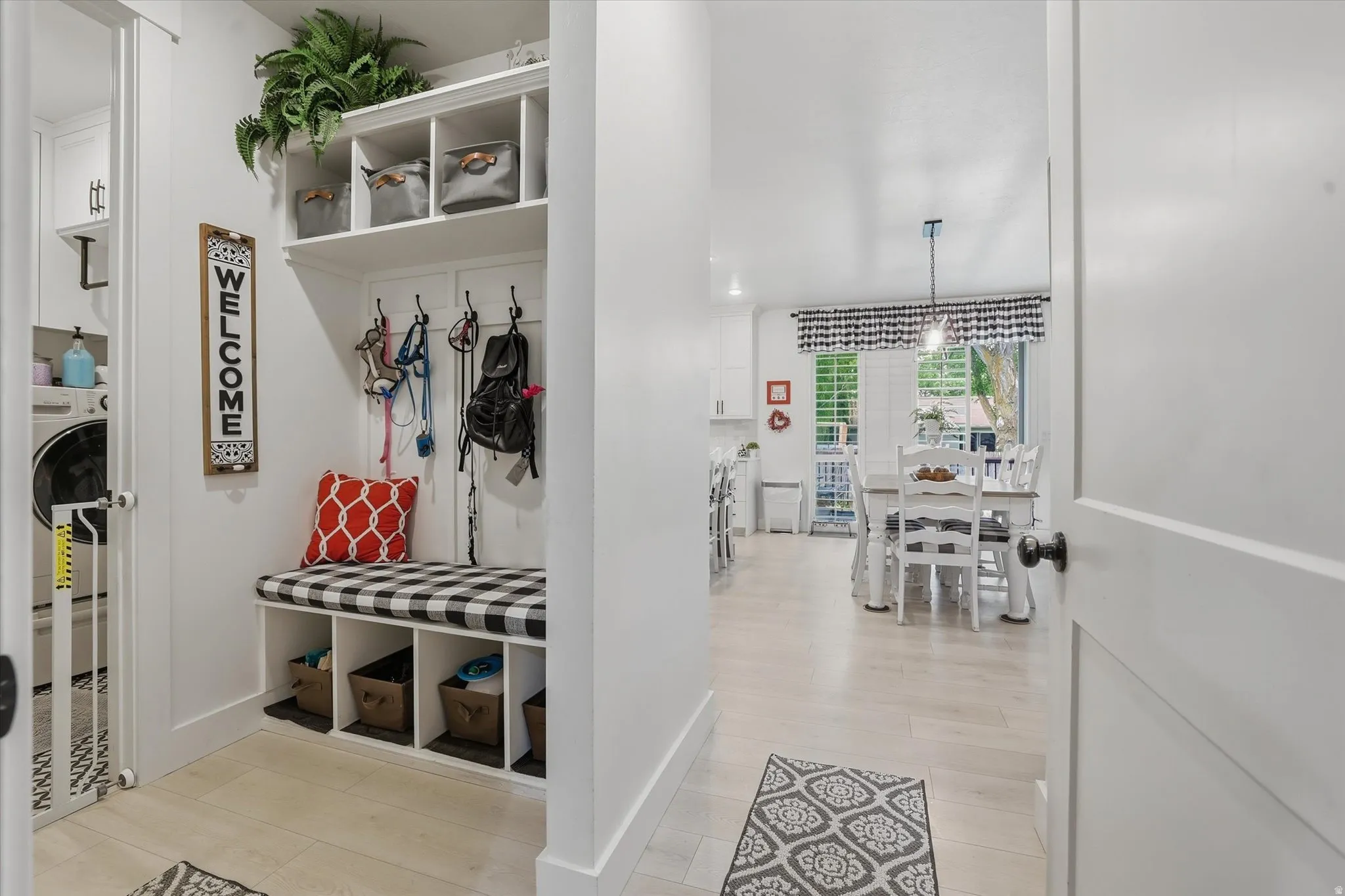 Entryway featuring a built-in mudroom bench with cubby storage and coat hooks, wood-finish flooring, and a laundry area with built-in cabinetry