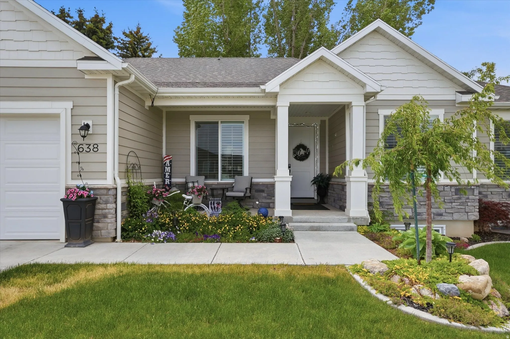 Exterior facade featuring light-colored siding, a covered front porch with white columns, and stone accents