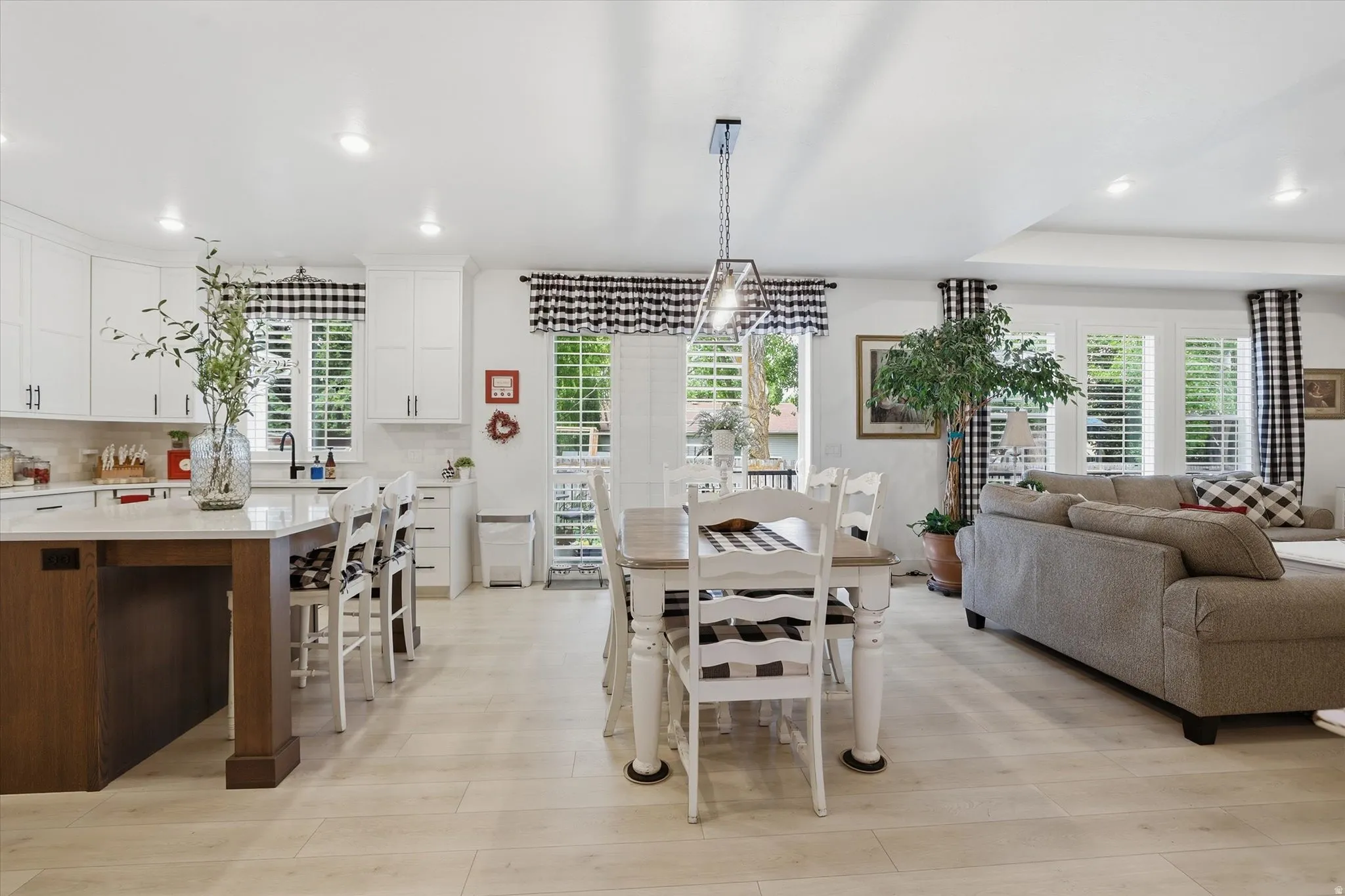 Open-concept interior featuring light wood-finish flooring, recessed lighting, and white plantation shutters