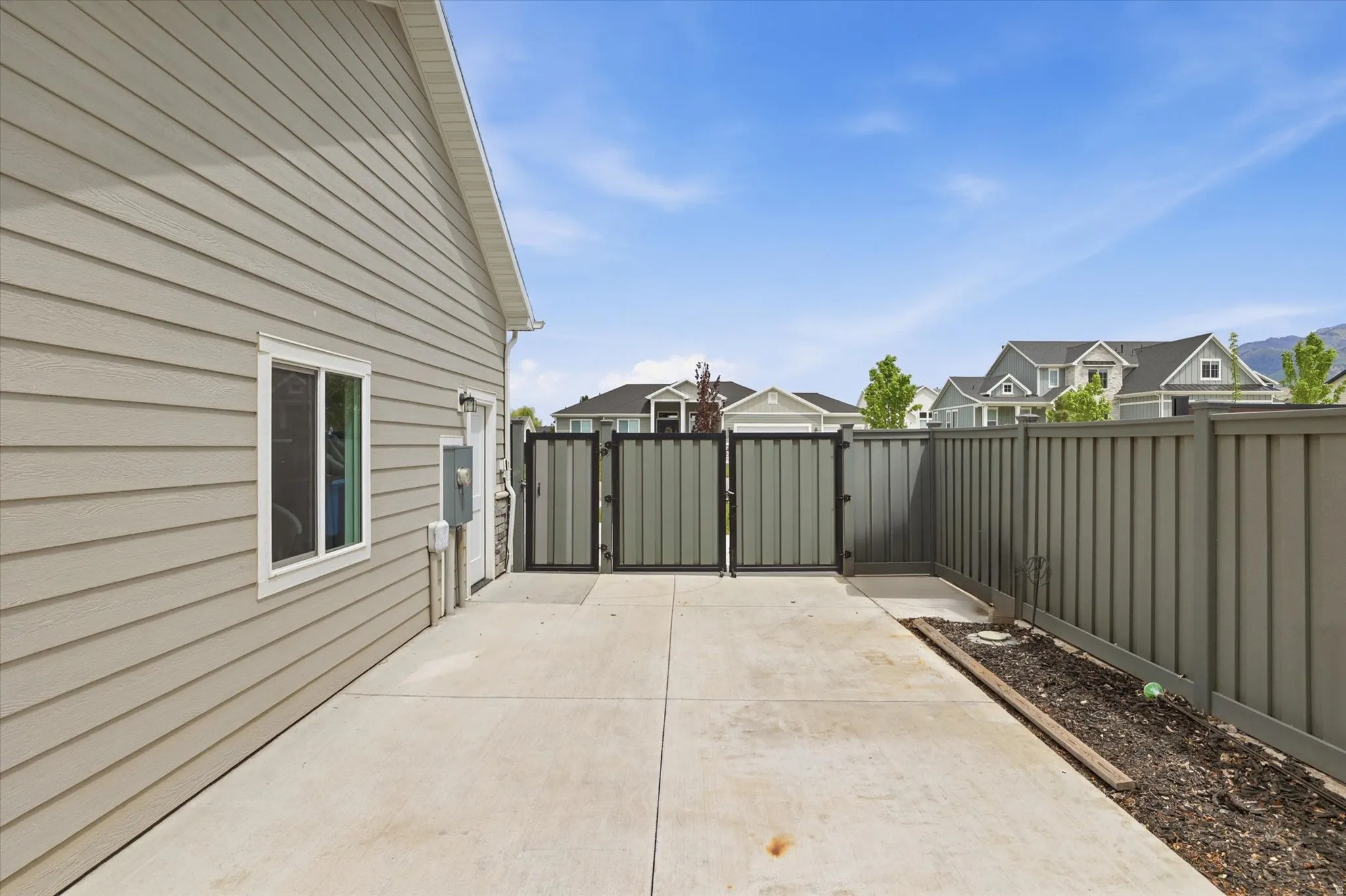 Spacious concrete patio with a full privacy fence and a gated entry