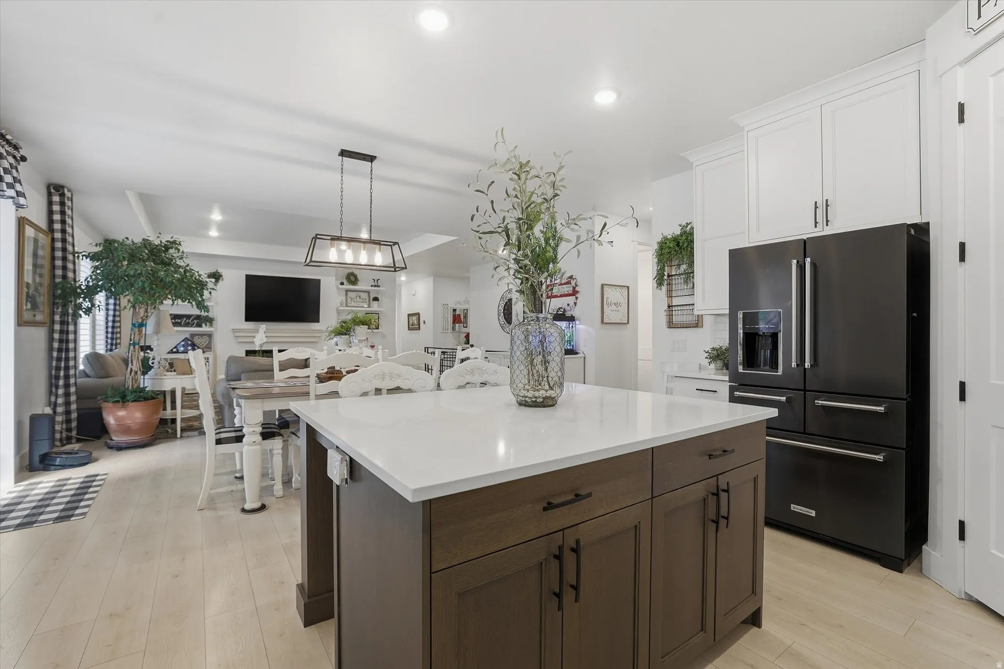 Kitchen featuring a dark wood-finish island with a white countertop and contrasting white cabinetry, a black French door refrigerator, and recessed lighting