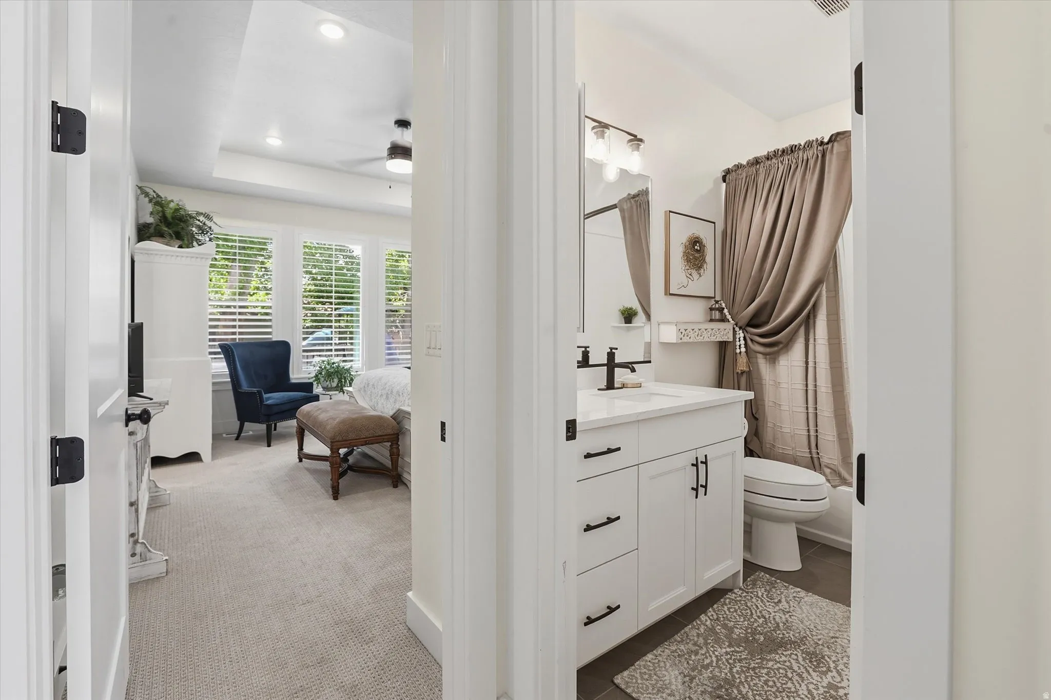 Bathroom featuring a white vanity with a white countertop and matte black hardware, paired with a toilet and a shower with a taupe curtain