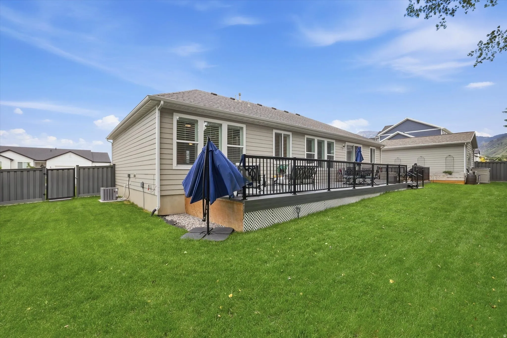 Expansive backyard featuring a large elevated deck with black railings, a well-maintained lawn, privacy fencing, and exterior siding