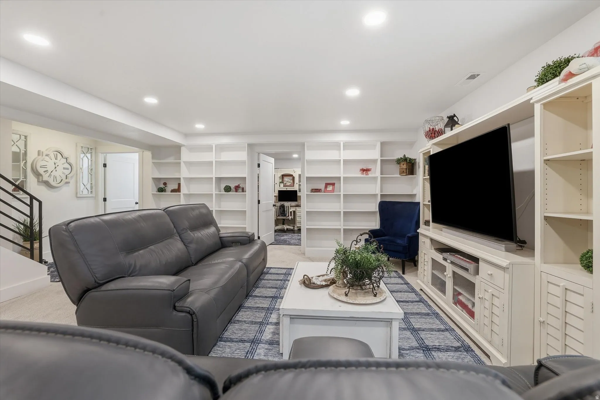 Spacious lower level featuring recessed lighting, extensive built-in shelving, white trim, and a contemporary staircase with black metal railing